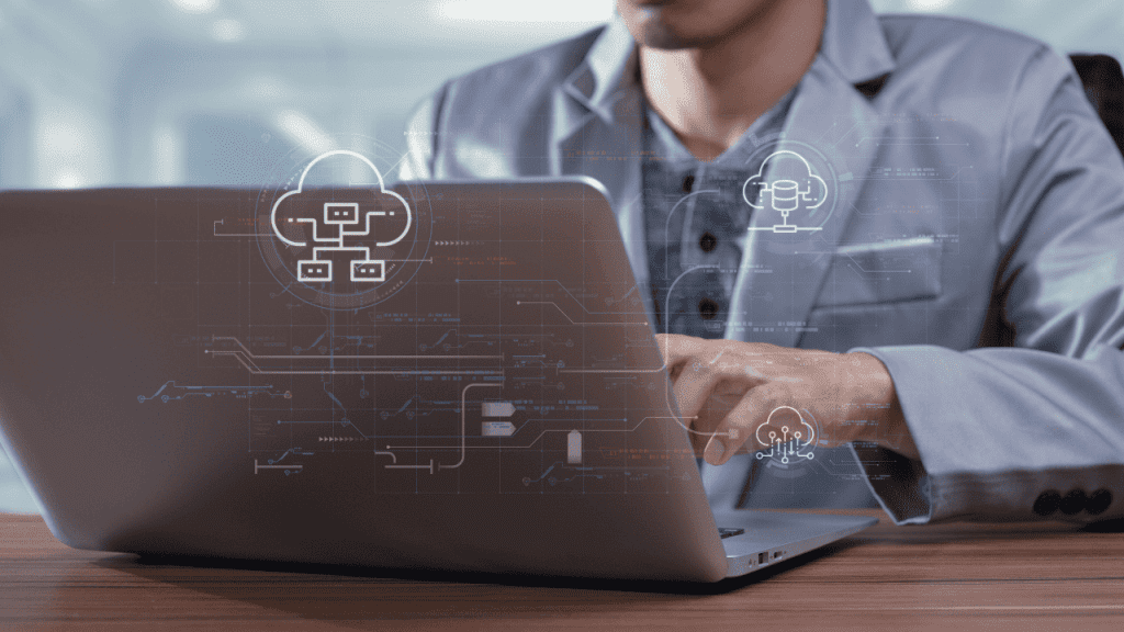 Pessoa usando notebook em ambiente corporativo, com ícones digitais de cloud, dados e inteligência artificial sobrepostos à imagem, representando soluções em nuvem e tecnologia.